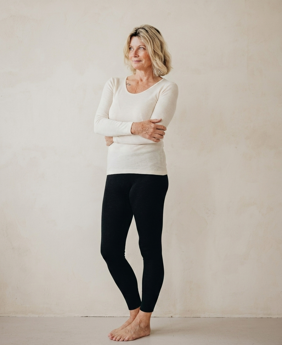Woman wearing a white angora and silk long-sleeve top and angora and wool black leggings against a plain background