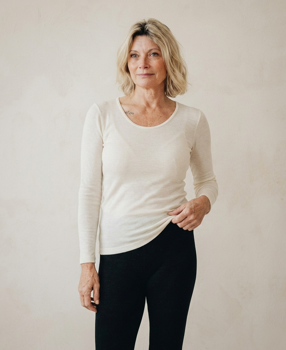 Woman wearing a white angora and silk long-sleeve shirt and black pants against a plain background