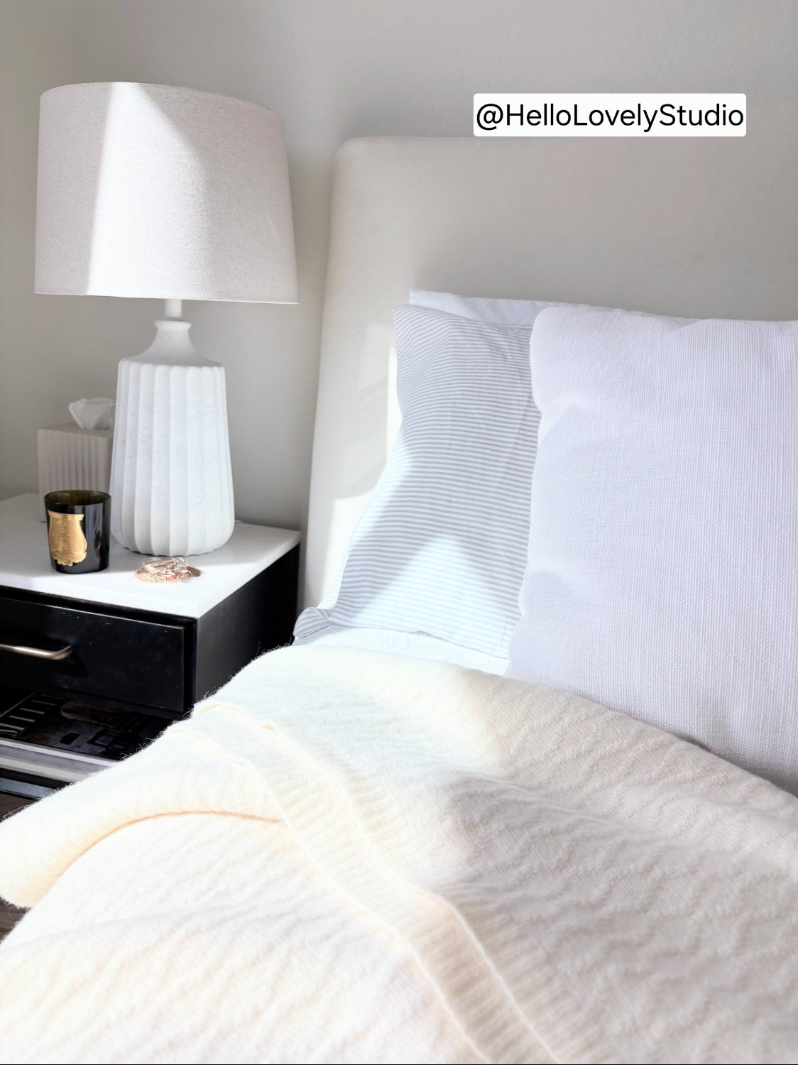 silverlyne-angora-wool-blanket-by HelloLovelyStudio. Neatly made bed with white bedding and pillows in a bedroom setting, featuring a lamp on a nightstand.